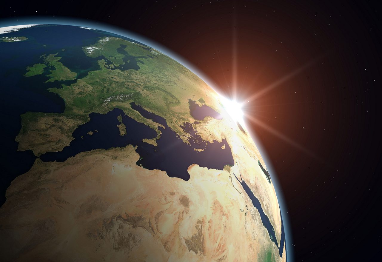 Earth from space, sun glaring on the horizon
