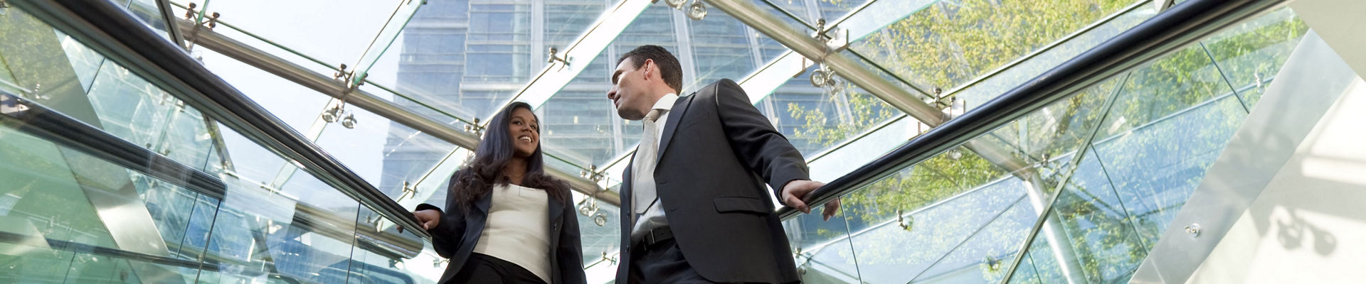 Two employees riding escalator in a high-tech building