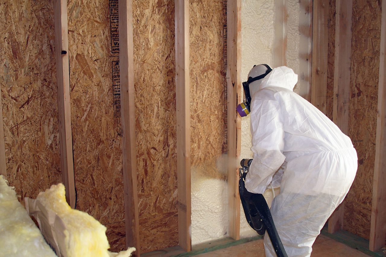 Hombre aplicando aislamiento de espuma en aerosol con soplador