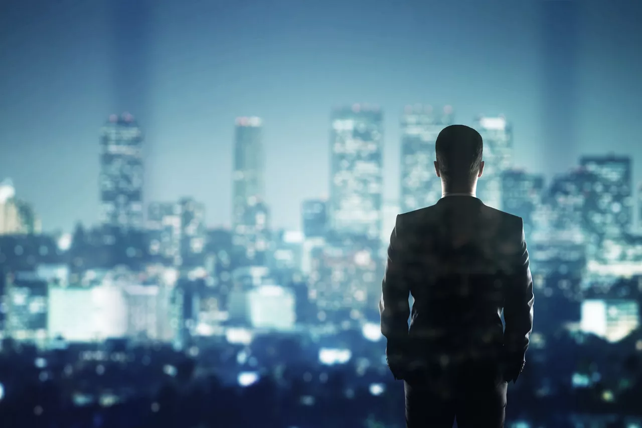 businessman in suit looking to night city The silohuette of a businessman in a suit looking out at the city at night. / 123rf Image #31864265