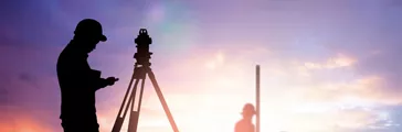 silhouette survey engineer working  in a building site over Blurred construction worker on construction site Silhouette of a survey engineer over a blurred worker on a construction site