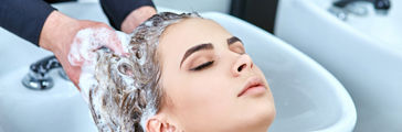 Young woman getting her hair washed in a salon by hairdresser