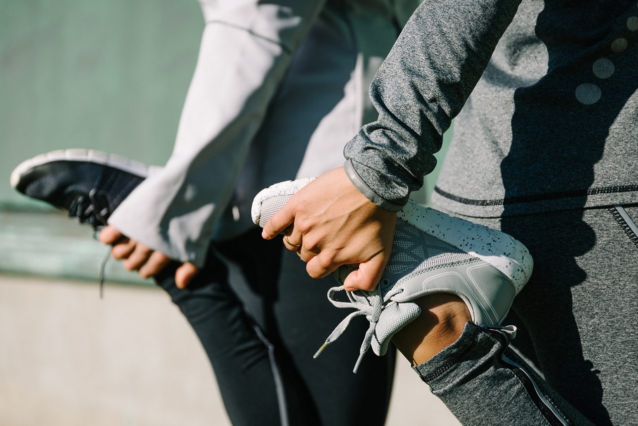 Closeup of two woman grabbing feet to stretch legs before or after a workout or run