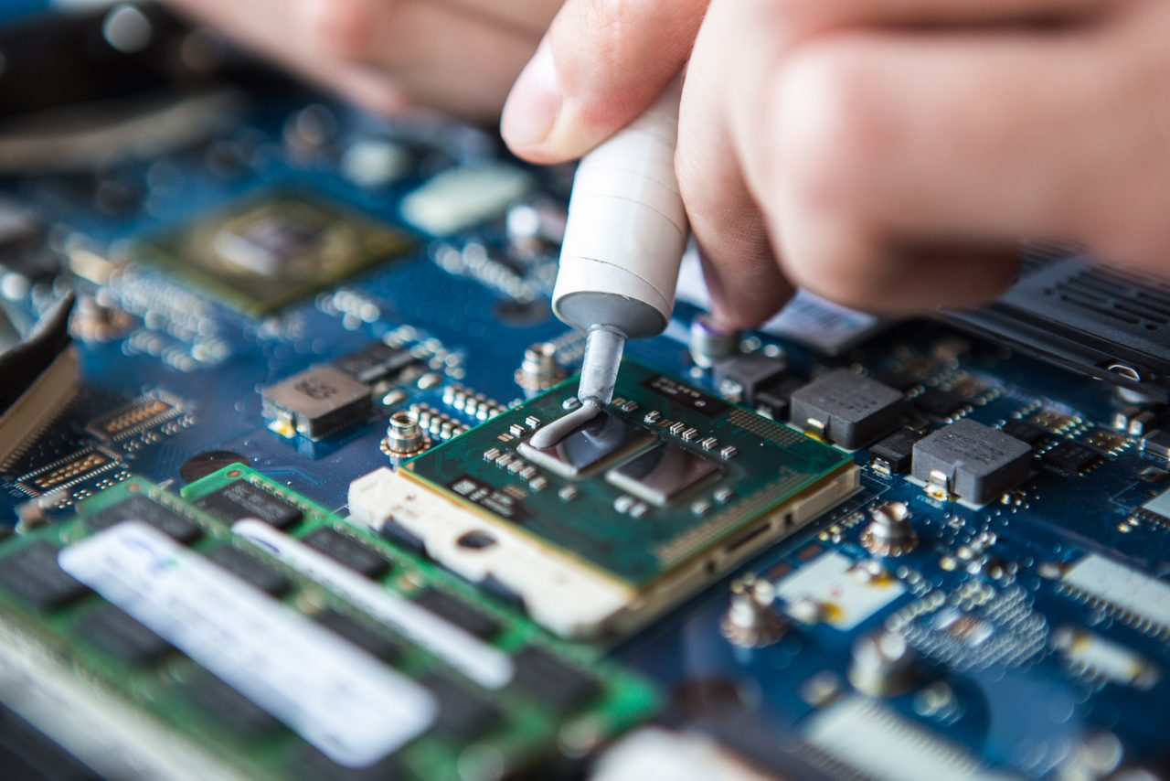 Person applying thermal paste on an electronic motherboard