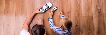 Unrecognizable father with his son playing with cars. Studio shot on wooden background.