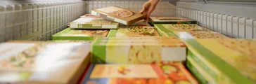 Man selecting a frozen pizza at a grocery store