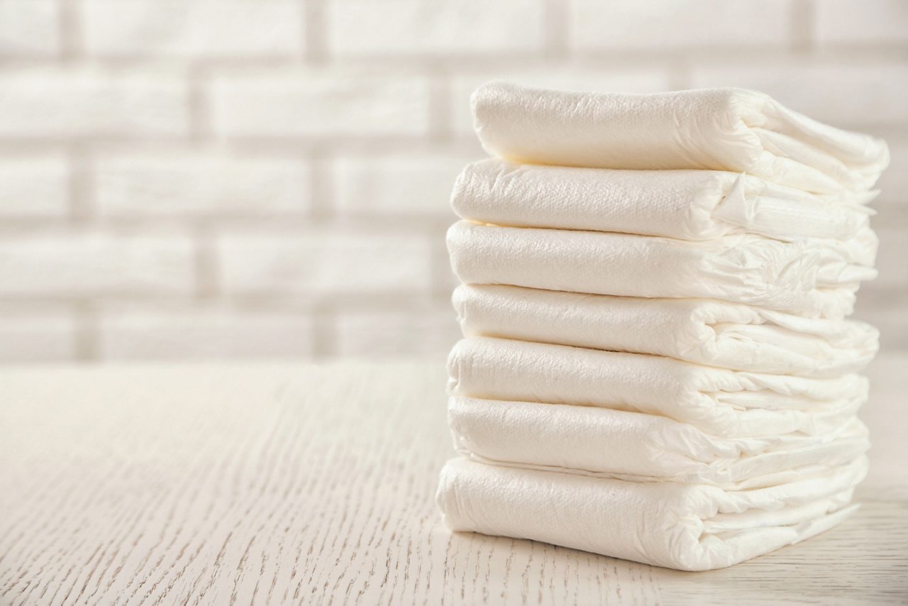 Stack of white diapers on white wood table 