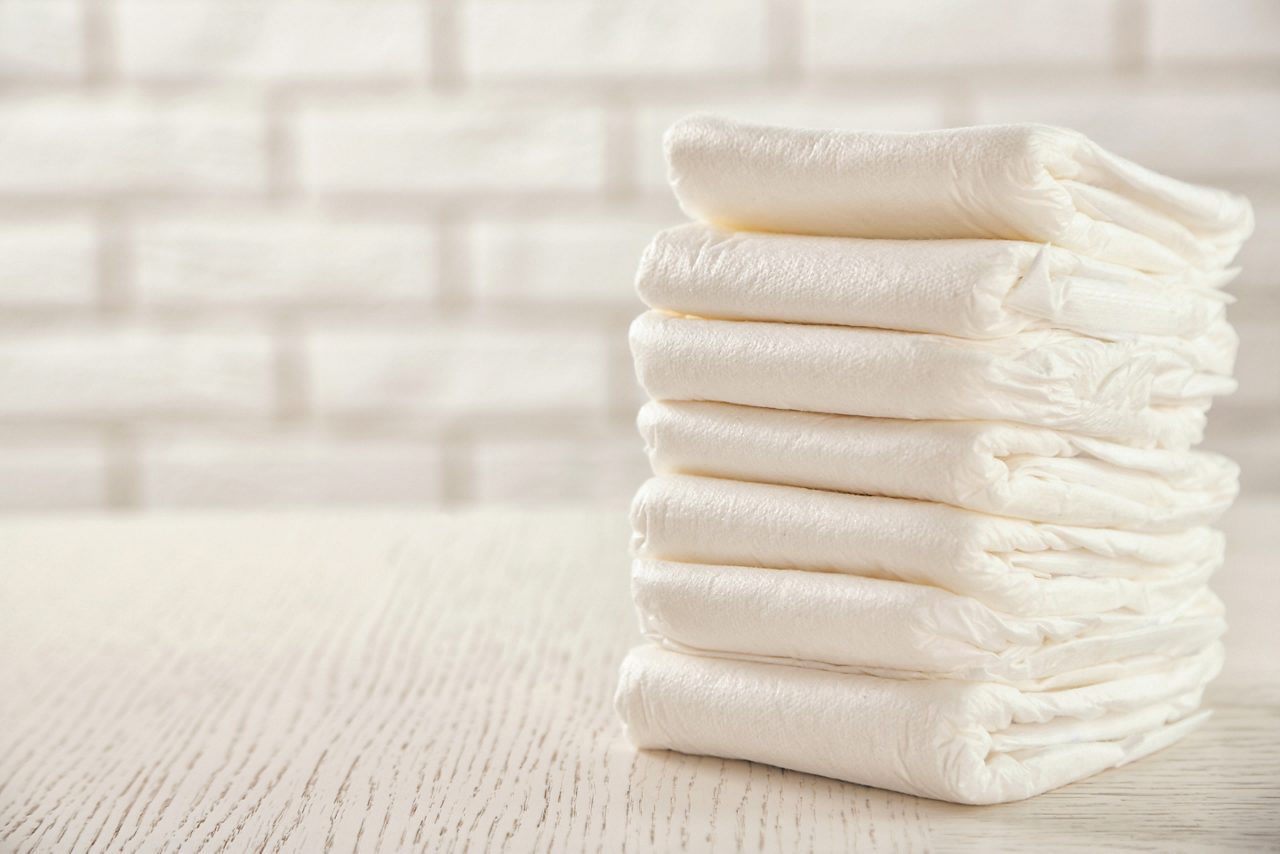 Stack of white diapers on white wood table 