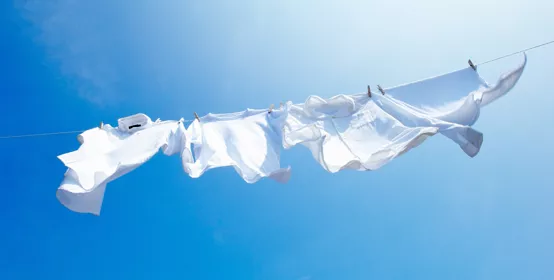 White clothes blowing in wind on clothes line with blue sky