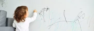 Baby girl drawing on wall