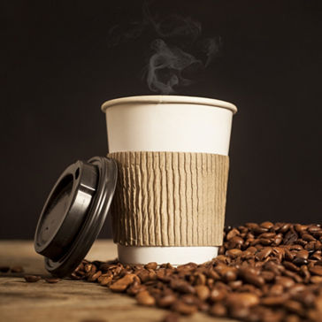 Vaso de café con protección térmica y tapa y granos a ambos lados 