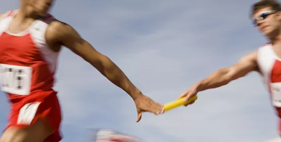 Athletes passing relay baton, motion blur