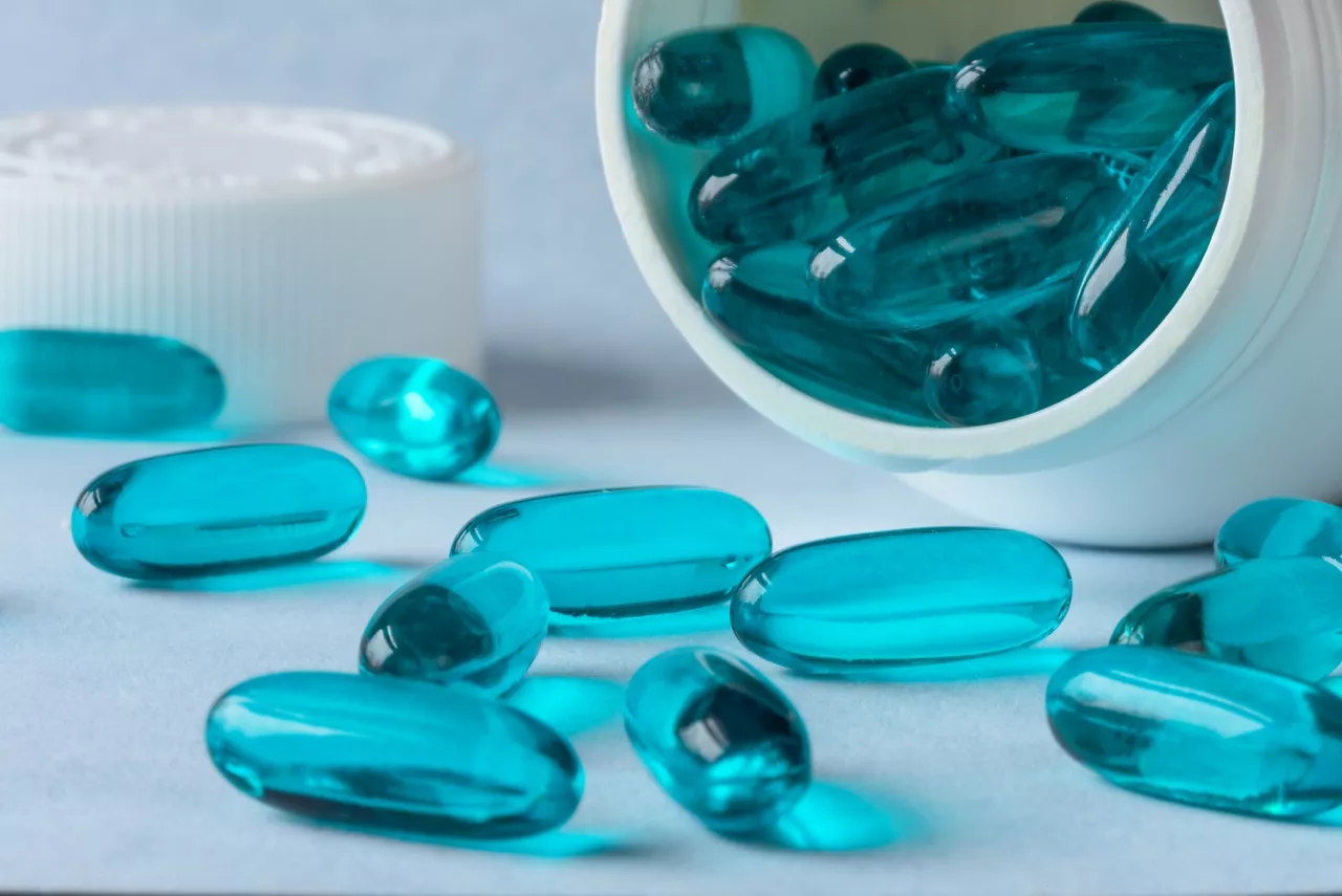 Blue gel pill capsules spilling out of bottle