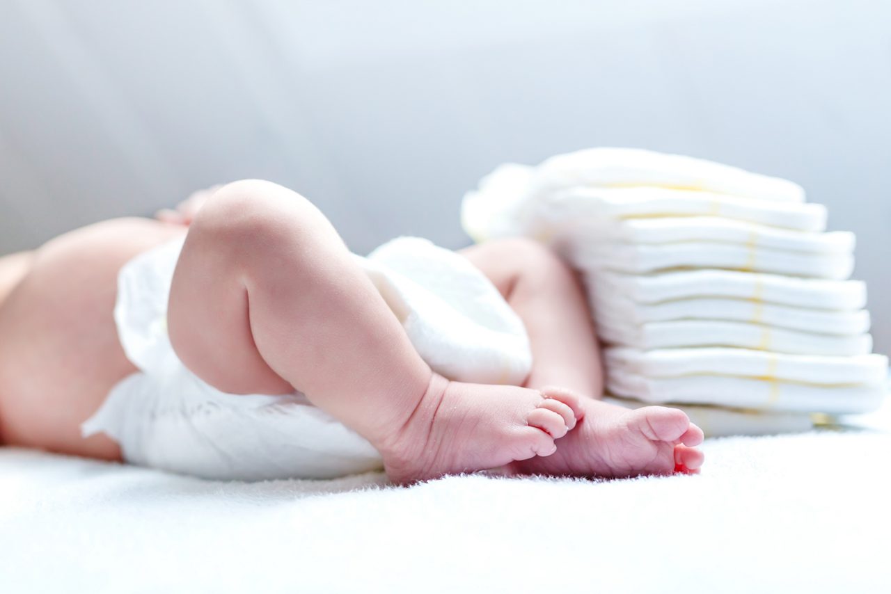 Feet of newborn baby on changing table with diapers 