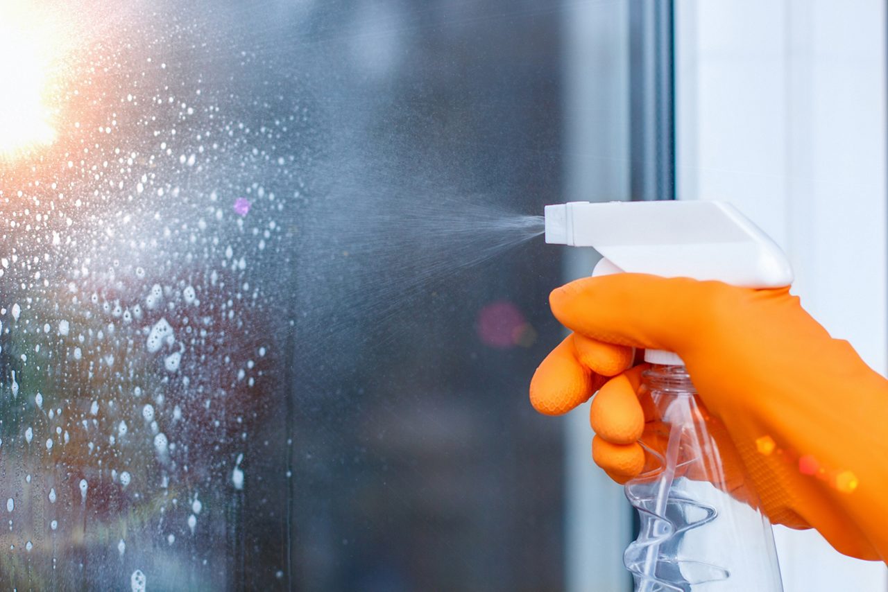 El trabajador limpia las ventanas con aerosol en la casa