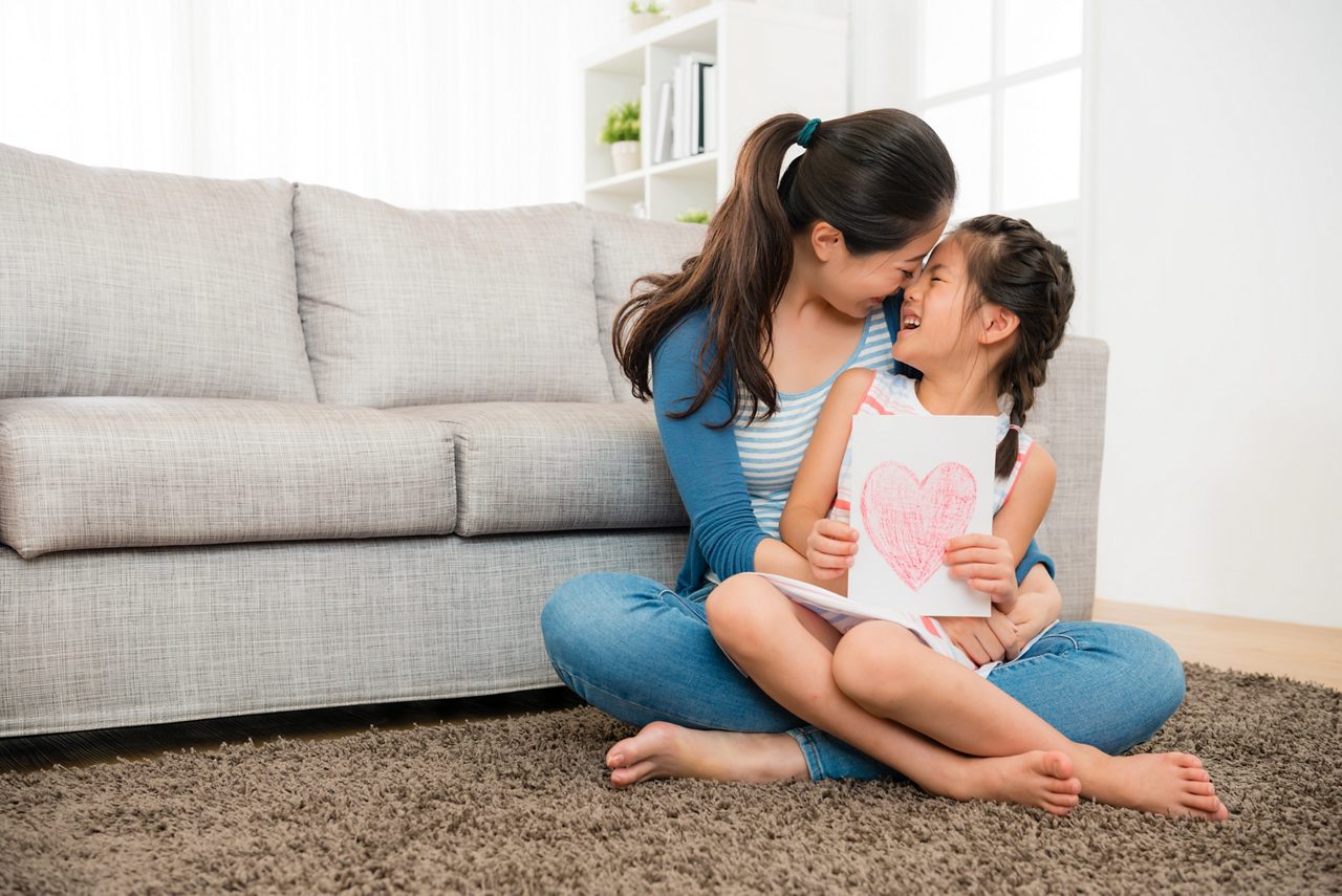 Mãe segurando a filha no sofá