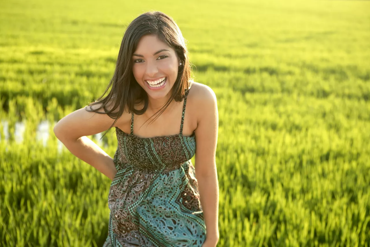 Beautiful brunette Indian young woman in the green rice fields meadow