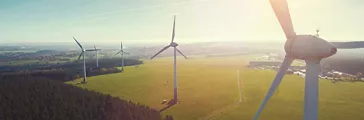 Wind turbines and agricultural fields on a summer day - Energy Production with clean and Renewable Energy - aerial shot