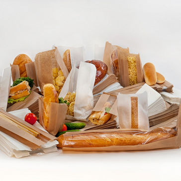 Diferentes panes y sándwiches en empaque de papel contra un fondo blanco 