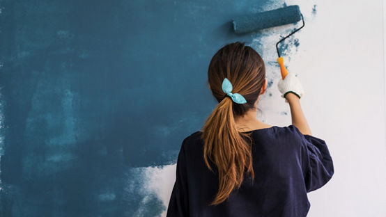 Young Asian happy woman painting interior wall