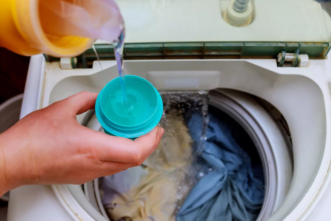 Woman hand pouring liquid detergent into the washing machine