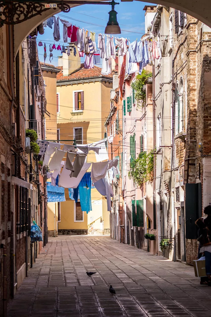 Tight small street with clothes drying on lines hanging between old buildings