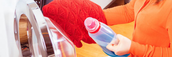 Woman at home doing laundry in washing machine.