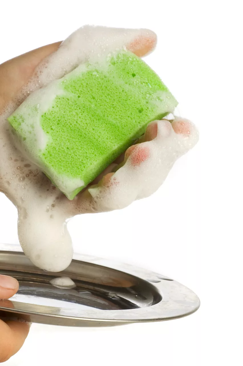 Hand washing plate with a green sponge with a lot of suds on a white background