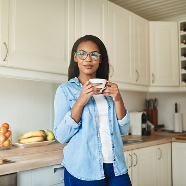 mulher pensando enquanto bebe uma xícara de café na cozinha em casa