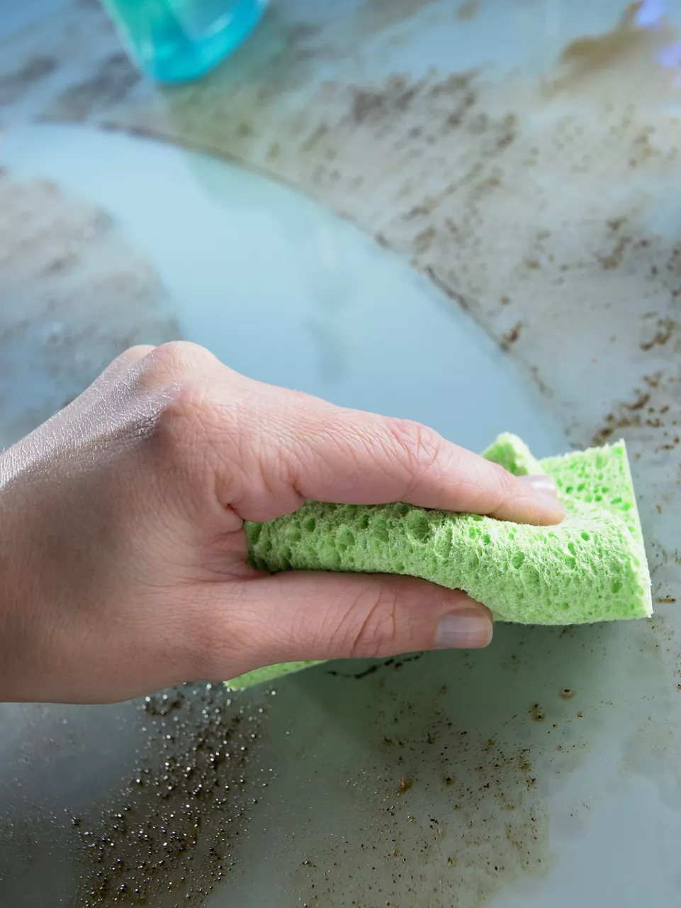 Hand cleaning grease and dirt off counter with a sponge