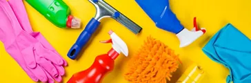 Cleaning supplies, gloves, bottles on yellow background