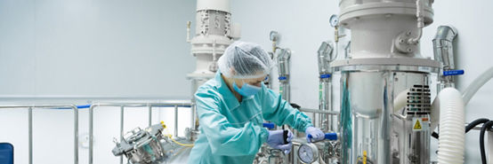 Pharmaceutical factory woman worker in protective clothing operating production line in sterile environment