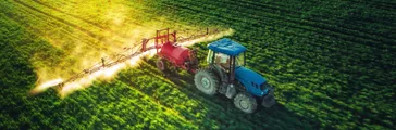 Blue tractor spraying field 