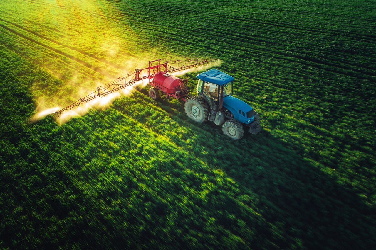 Tractor plowing and spraying on field