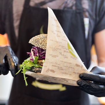 Person putting burger into paper packaging 