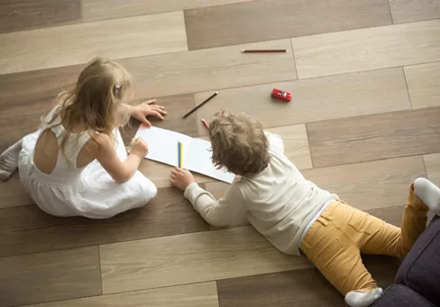 Kids sister and brother playing drawing together on wooden warm floor in living room, creative children boy and girl having fun at home, siblings friendship, underfloor heating concept, top view
