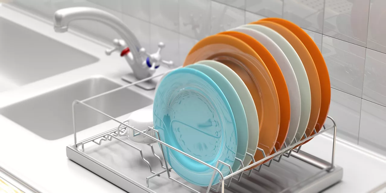 Dish drying rack with colorful clean plates on a white kitchen sink counter