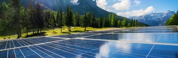 Solar cell panel in country landscape against sunny sky and mountain backgrounds