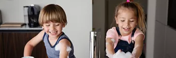 Kids playing with suds while washing dishes in a modern sink