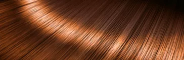 Closeup view of a section of glossy straight ginger hair in a wavy style 