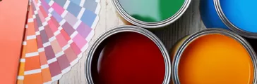 Cans with paint and color palette on wooden background, top view