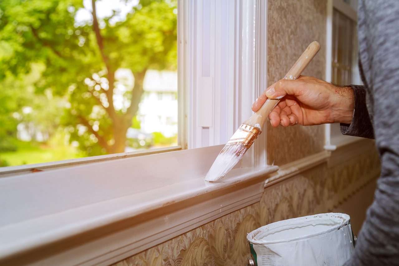 Person painting window trim at home
