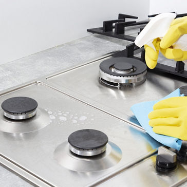 Cleaning a gas stove with kitchen utensils, household concepts, or hygiene and cleaning