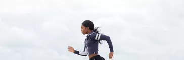 Full body side portrait of african american woman running by the beach