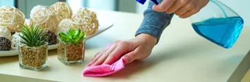 Wiping dust from table with a rag and spray