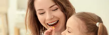 Little daughter giving pill to her mother at home