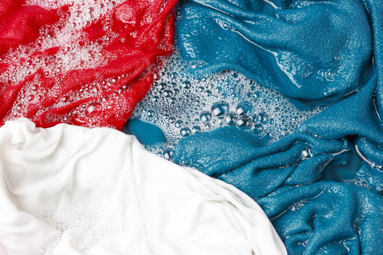 Colorful clothes washed with a basin with soap bubbles, close-up, top view