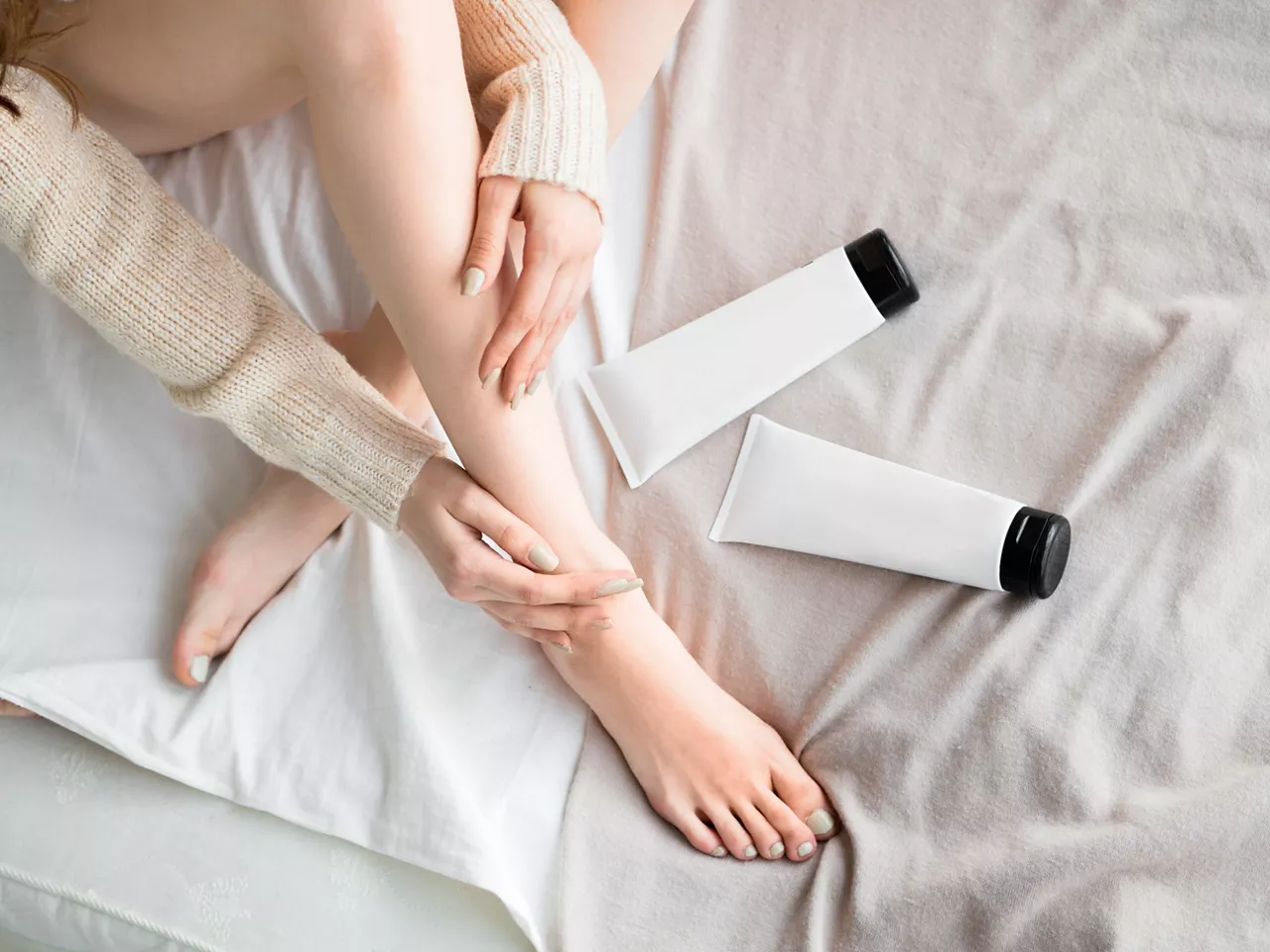 Woman putting ointment or moisturizer cream on her legs. Mock up. Skin care concept