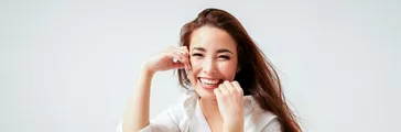 Beauty fashion portrait of smiling sensual asian young woman with dark long hair in white shirt on white background