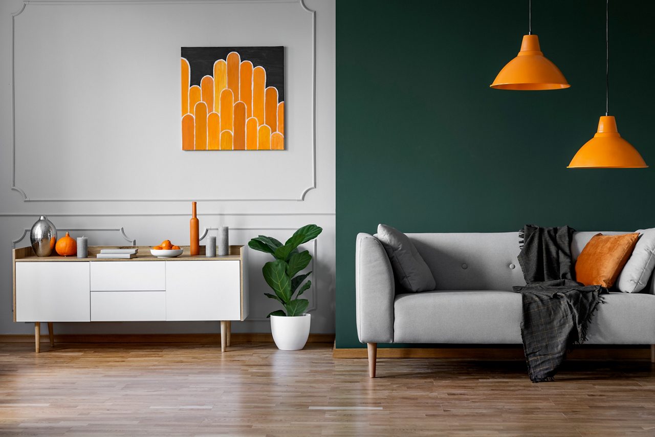 Pared verde y gris del elegante interior de la sala de estar con muebles de madera blanca y un sofá gris